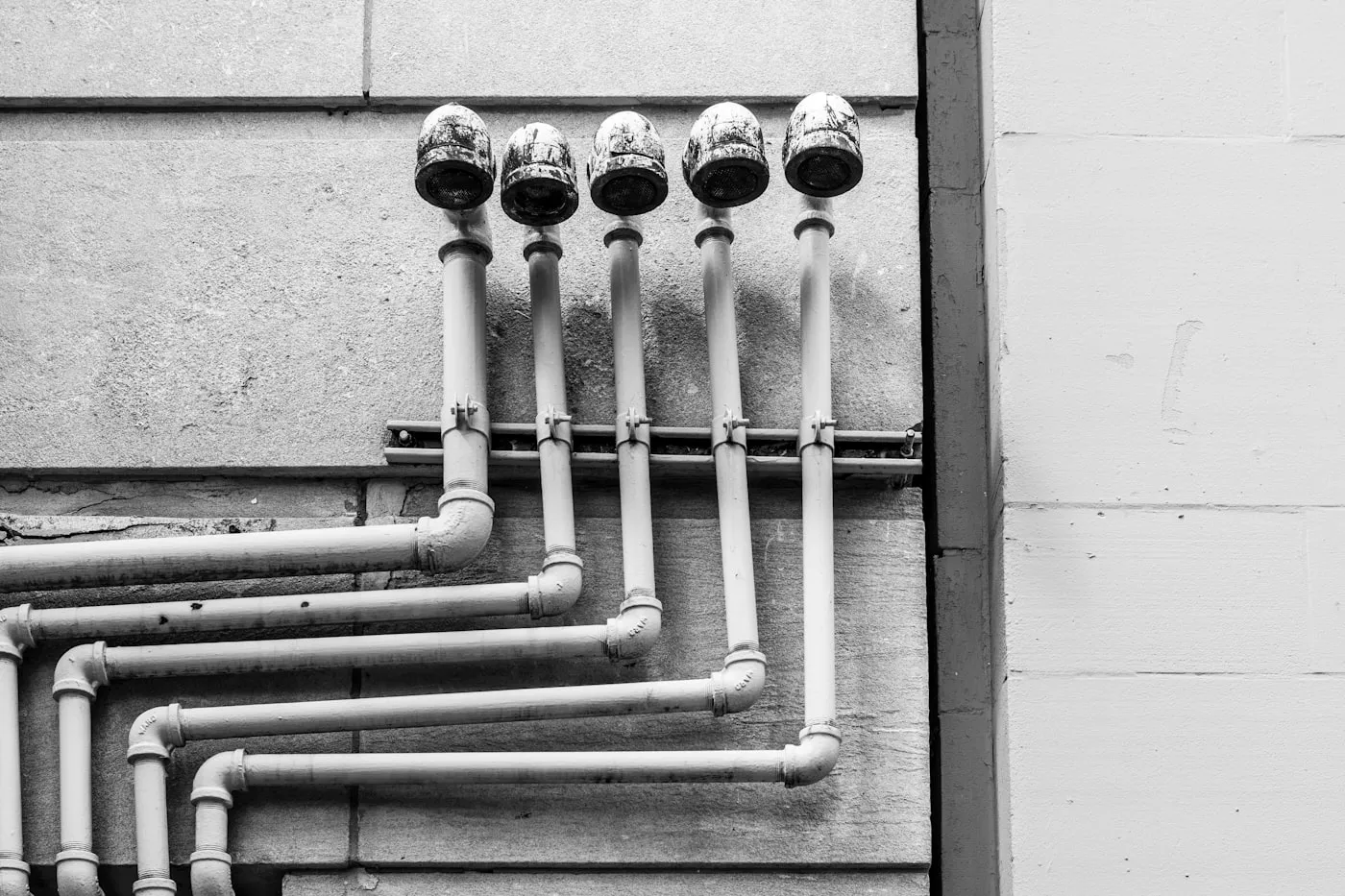 Cinq colonnes en applique sur un mur, robinets d’arrêt alignés en tête et coudes repris en pied